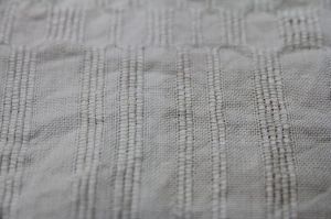 Lähikuva kutistetun kankaan pinnasta, kudottu aivina 16:lla. Huomaa loimen aiheuttama väriero: vasemmalla merseroimaton, oikealla merseroitu loimilanka.